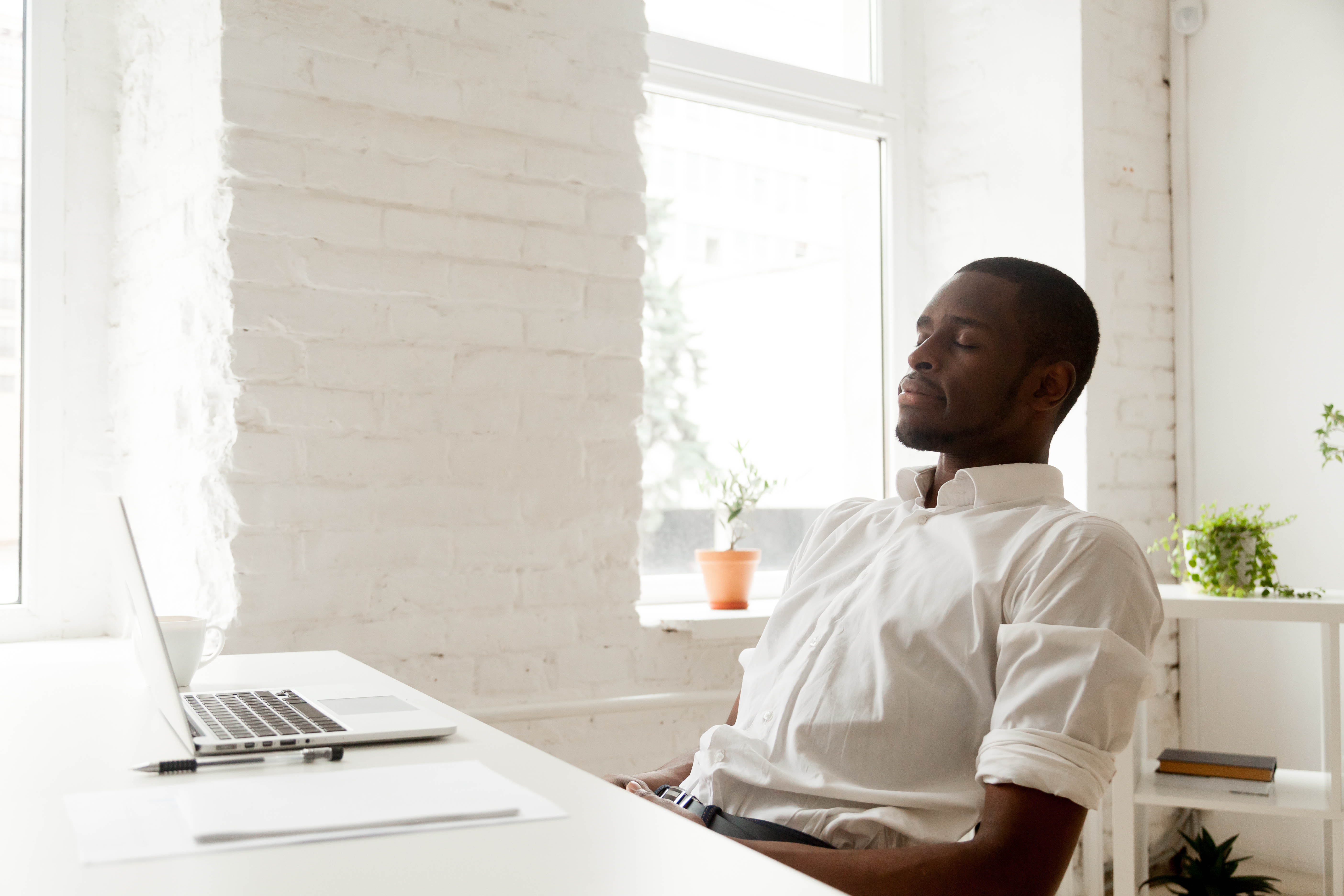 Middle aged man sitting at his desk, leaning back with his eyes closed